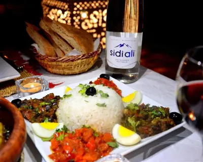 a plate of food with rice and a bottle of wine at spirit desert camp in Merzouga