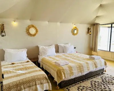 a bedroom with two beds and two mirrors on the wall at spirit desert camp in Merzouga