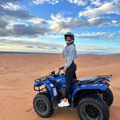 a person standing on a blue atv in the desert at spirit desert camp in Merzouga