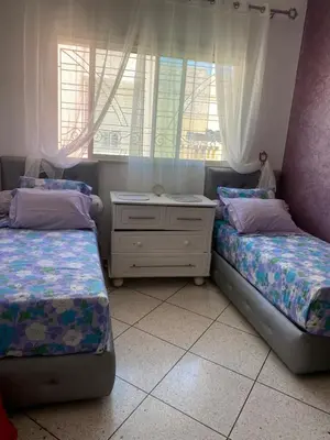 a bedroom with two beds and a dresser and a window at Appartement Yasin Meknes in Meknès