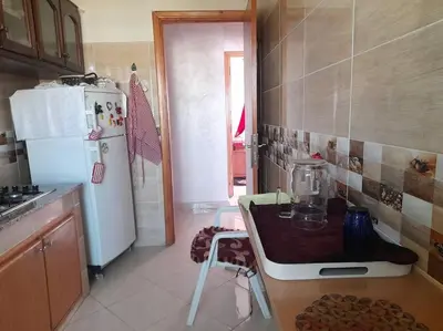 a kitchen with a table and a white refrigerator at Appartement au centre de la ville de Meknès in Meknès