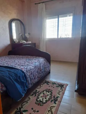a bedroom with a bed and a mirror and a rug at Appartement au centre de la ville de Meknès in Meknès