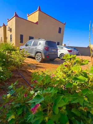 two cars parked in a parking lot in front of a building at Dar Amrad in Merzouga