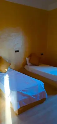 a bedroom with two beds with blue sheets at Dar Amrad in Merzouga