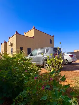 two cars parked in a parking lot in front of a building at Dar Amrad in Merzouga