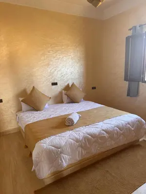 a bedroom with a large bed with white sheets at Dar Amrad in Merzouga