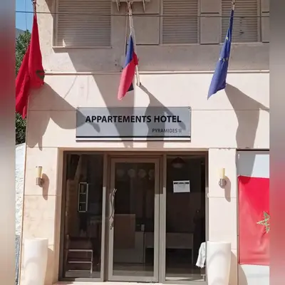 a building with two flags in front of it at APPARTEMENTS HOTEL PYRAMIDES in Taza