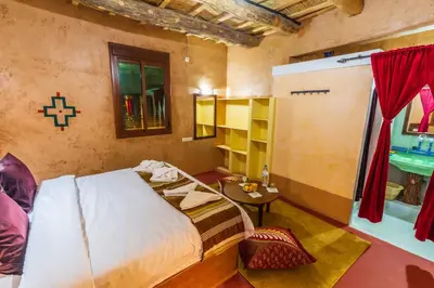 a bedroom with a bed and a table in a room at Palais Ksar Lamane in Aït Ben Haddou