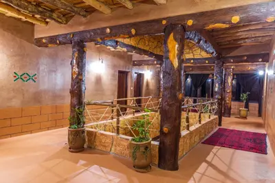 a large room with wooden beams and plants at Palais Ksar Lamane in Aït Ben Haddou