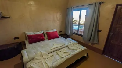 a bedroom with a bed with red pillows and a window at Palais Ksar Lamane in Aït Ben Haddou