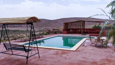 a resort with a pool and chairs and a building at Palais Ksar Lamane in Aït Ben Haddou