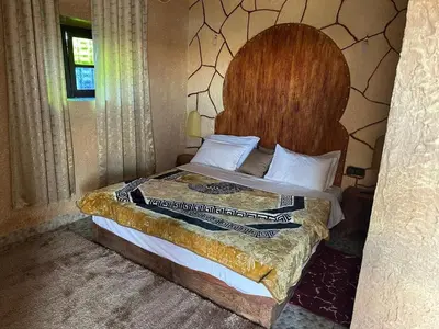 a bedroom with a bed with a large wooden headboard at DAR AL QANASS IMANE in Midelt