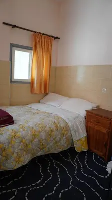 a bedroom with a bed and a dresser and a window at Hôtel Restaurant ASGAOUR in Amlouggui
