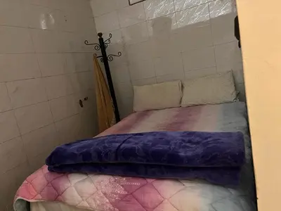 a small bedroom with a bed with purple blankets at Hôtel Restaurant ASGAOUR in Amlouggui
