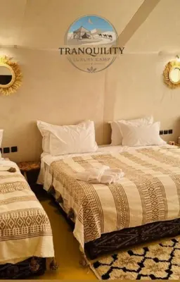 two beds in a room with a sign on the wall at Tranquility Luxury Camp in Merzouga
