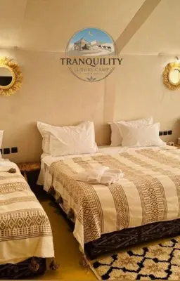 two beds in a room with a sign on the wall at Tranquility Luxury Camp in Merzouga