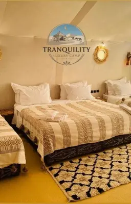 a bedroom with two beds and a sign on the wall at Tranquility Luxury Camp in Merzouga