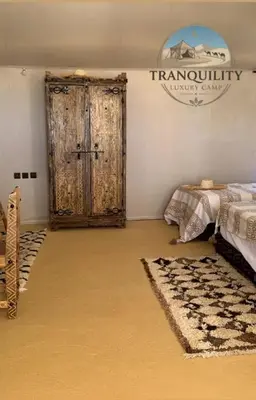 a bedroom with a bed and a wooden door at Tranquility Luxury Camp in Merzouga