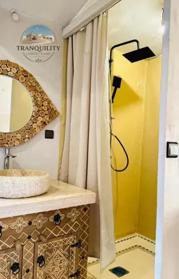 a bathroom with a shower with a sink and a mirror at Tranquility Luxury Camp in Merzouga