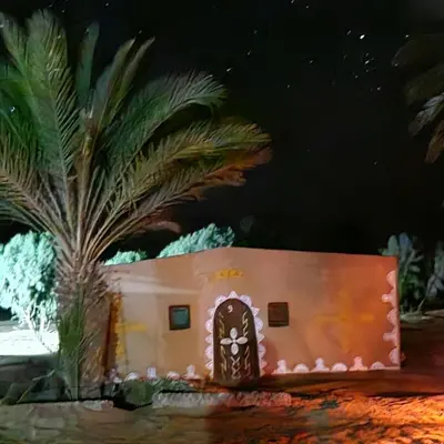 a model of a house in front of a palm tree at Camp Sahara Dunes in Mhamid