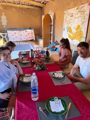 a group of people sitting around a table with food at Camp Sahara Dunes in Mhamid