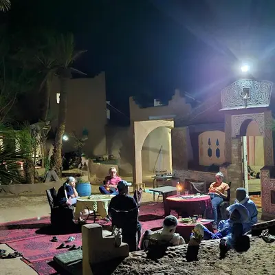 a group of people sitting around a table at night at Camp Sahara Dunes in Mhamid