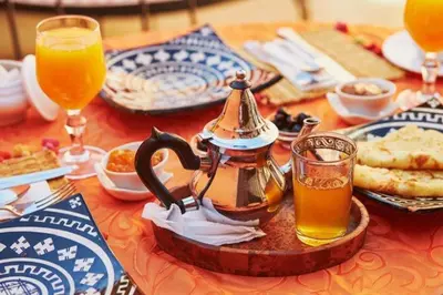 a table with a tea pot and glasses of orange juice at Camp Sahara Dunes in Mhamid