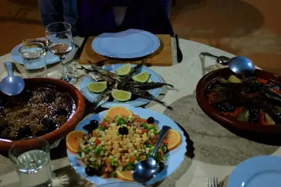 a table with plates of food and a bowl of food at Camp Sahara Dunes in Mhamid