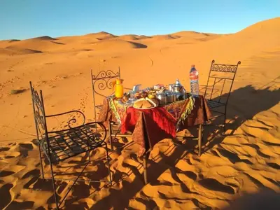 a table in the middle of the desert at Camp Sahara Dunes in Mhamid