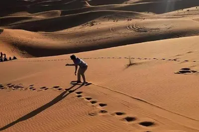 a man standing in the desert with footprints in the sand at Chez les habitants in Merzouga