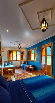 a bedroom with two beds and a blue wall at DAR EL HACHIMI EL IDRISSI in Ourika
