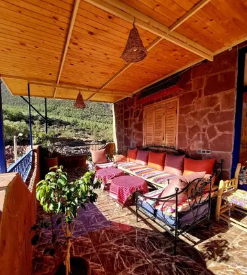 a screened in porch with a couch and a table at DAR EL HACHIMI EL IDRISSI in Ourika