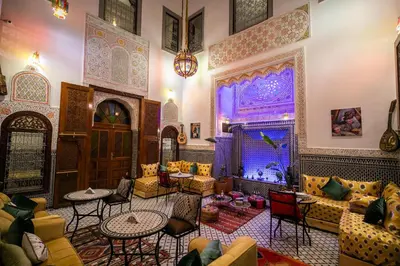 a living room with couches and tables and a large window at Riad Tarab Fes in Fès