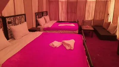 two beds in a room with pink sheets at Safari luxury desert camp in Merzouga