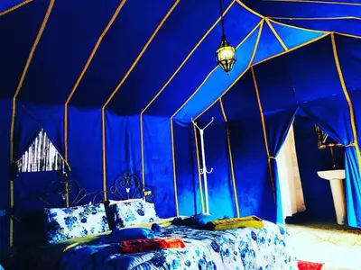 a blue room with a bed in a tent at Safari luxury desert camp in Merzouga