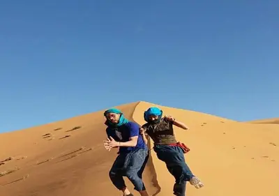 two men running down a sand dune at Safari luxury desert camp in Merzouga