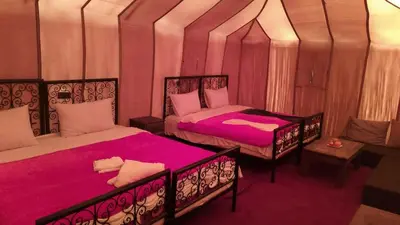 a room with two beds and a chair in it at Safari luxury desert camp in Merzouga