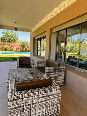 a patio with wicker chairs and tables and windows at Dar HAKIM piscine privée in Marrakech