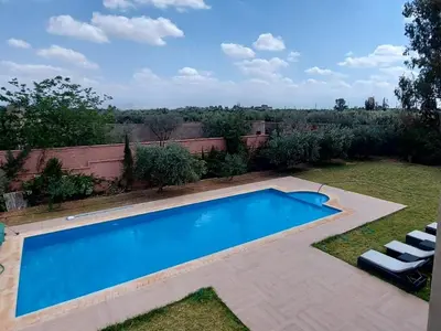 a swimming pool in a yard with two white chairs at Dar HAKIM piscine privée in Marrakech
