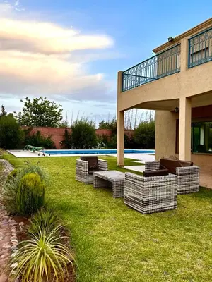 a group of chairs sitting in the grass next to a house at Dar HAKIM piscine privée in Marrakech