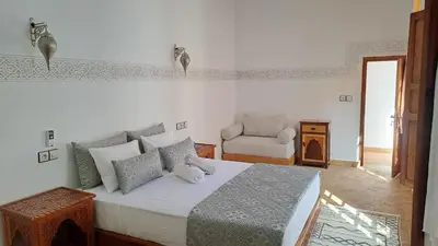 a bedroom with a large bed and a chair at Dar S'BAH in Fès