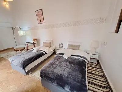 two beds in a white room with a table at Dar S'BAH in Fès