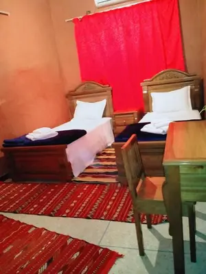 two beds in a room with a red curtain at Maison d'Hôtes Ghalil in Ouarzazate