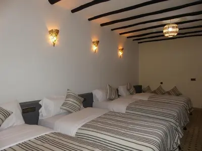 a group of three beds in a room at Riad La Luna in Merzouga