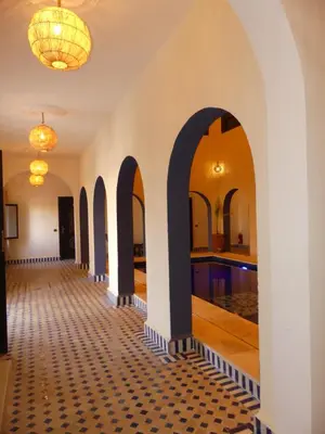 a hallway with arches and a pool in a building at Riad La Luna in Merzouga