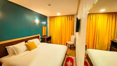 a bedroom with a large white bed and yellow curtains at Hôtel Belle Vue et Spa in Meknès
