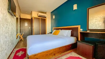 a bedroom with a bed and a blue wall at Hôtel Belle Vue et Spa in Meknès