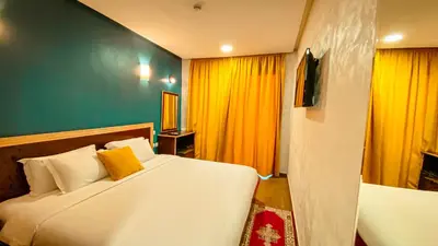 a bedroom with a large white bed with yellow curtains at Hôtel Belle Vue et Spa in Meknès