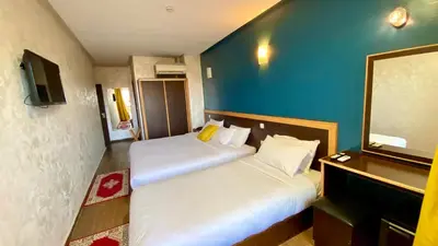 a room with two beds and a blue wall at Hôtel Belle Vue et Spa in Meknès