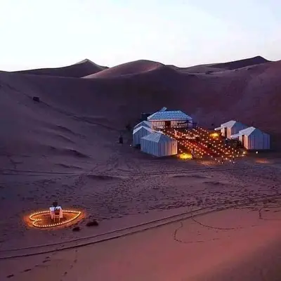 a group of buildings in the desert at night at Sahara Camp Light in Mhamid